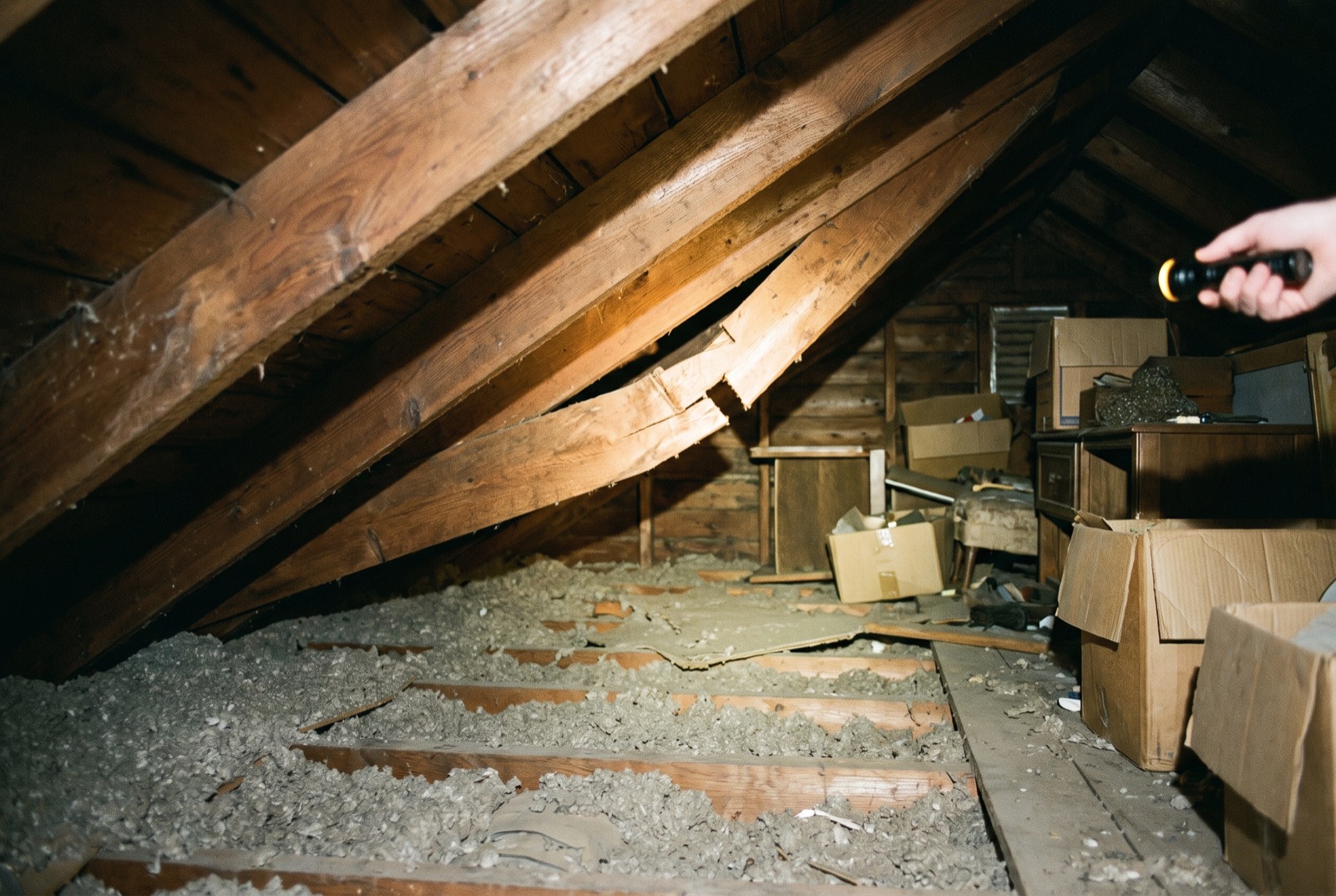 A flashlight on a cracked rafter in an attic