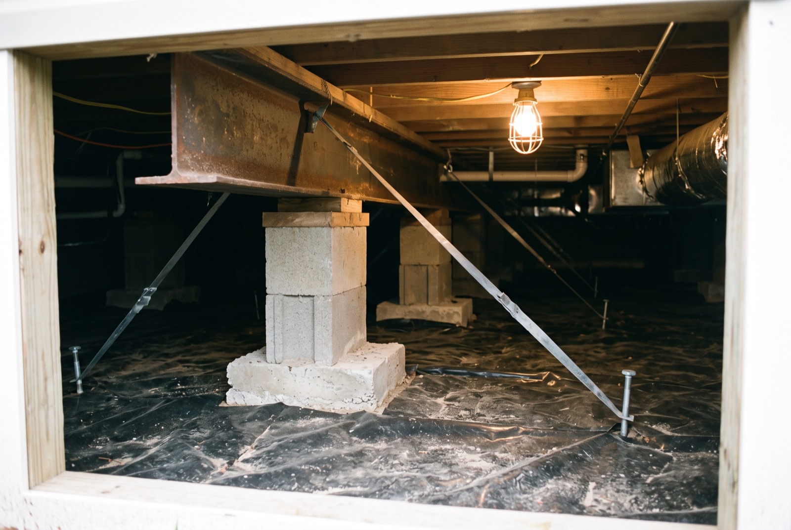 Steel frame, block piers, and tie-down straps under a manufactured home