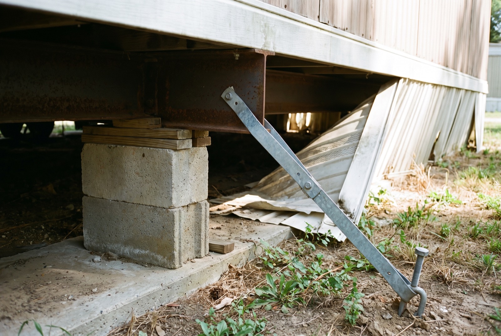 A block pier, footing, and anchor strap under a manufactured home